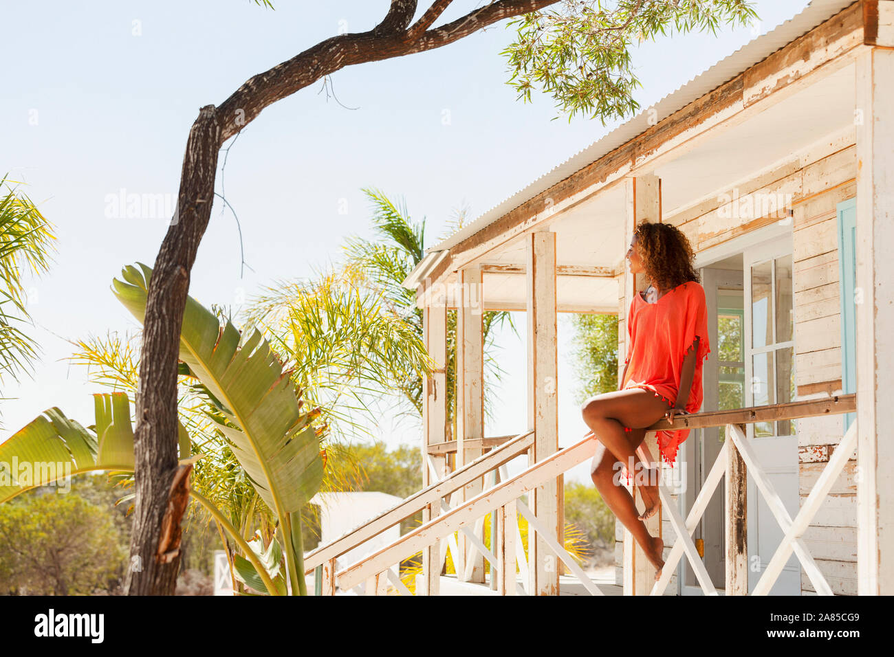 Young, serene woman relaxing on sunny beach hut patio Stock Photo