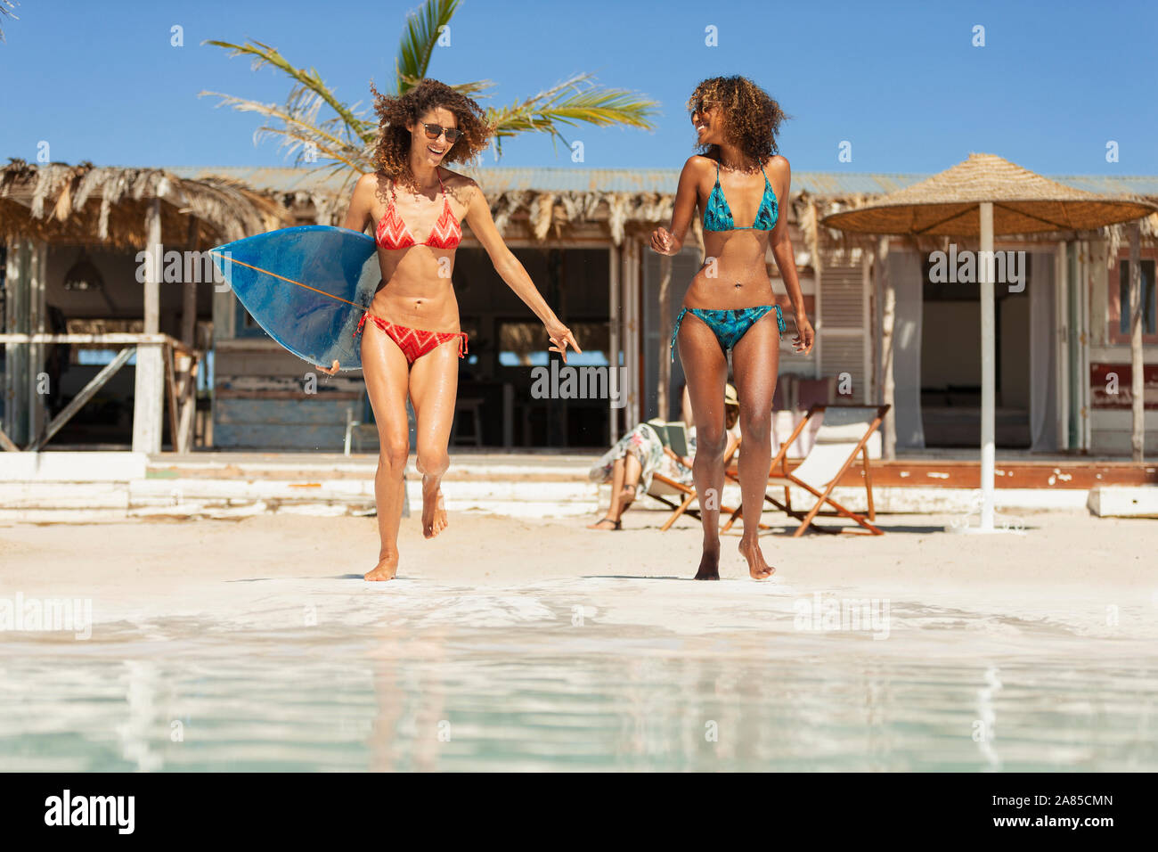 Carefree young women friends with surfboard on sunny beach Stock Photo