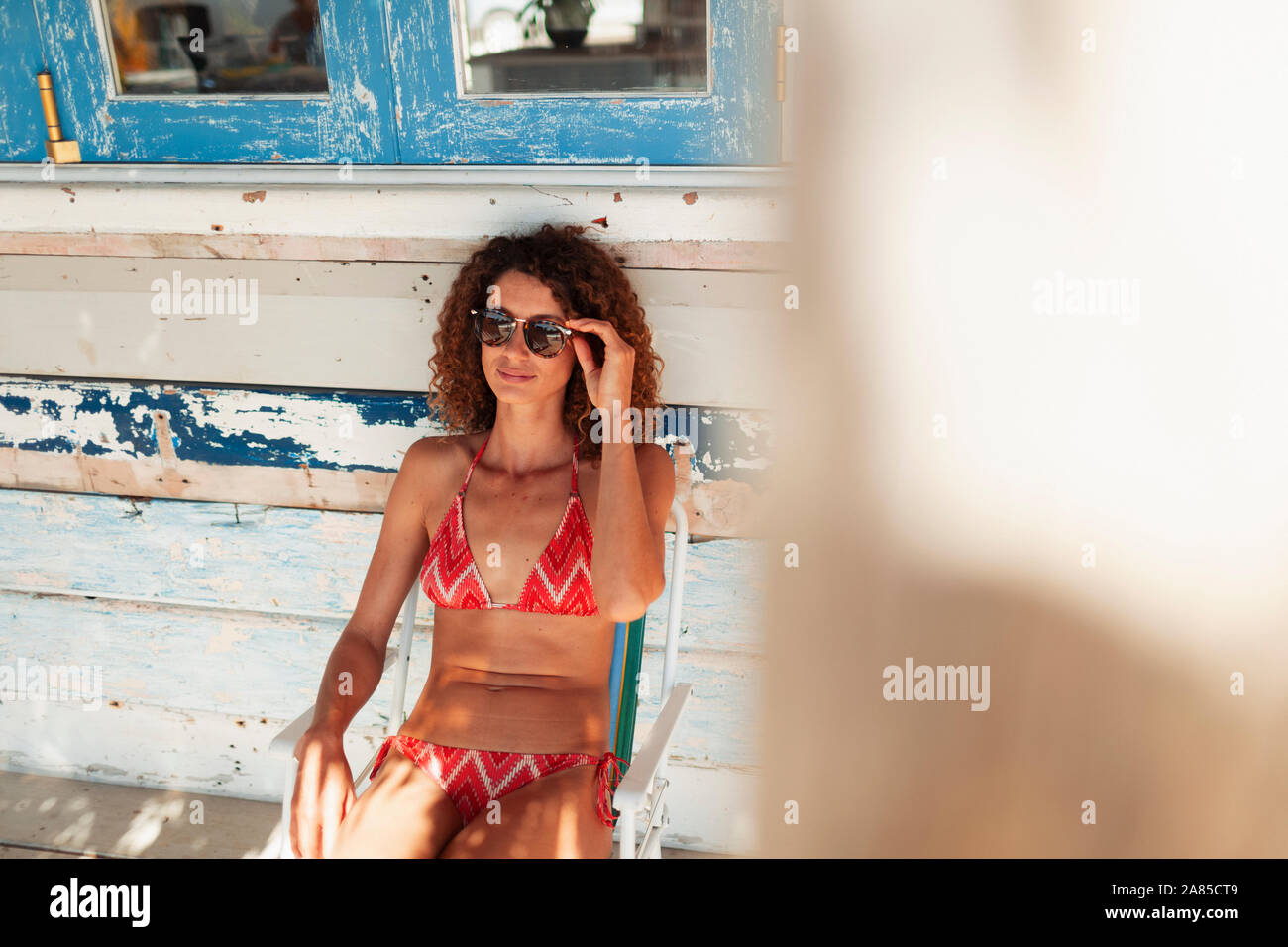 Young woman in bikini relaxing on beach hut patio Stock Photo