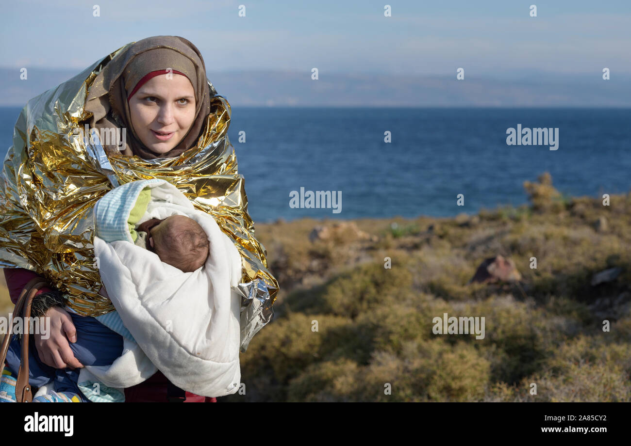 A Syrian refugee woman and her baby hike up a hill from a beach near Molyvos, on the Greek island of Lesbos, on October 30, 2015. Stock Photo