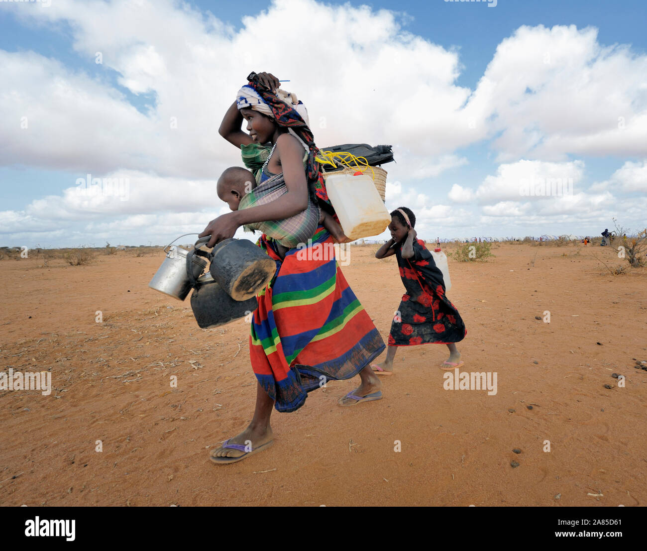 A mother and her children--newly arrived refugees--carry their belongings through the Dadaab camp in northeastern Kenya. Stock Photo