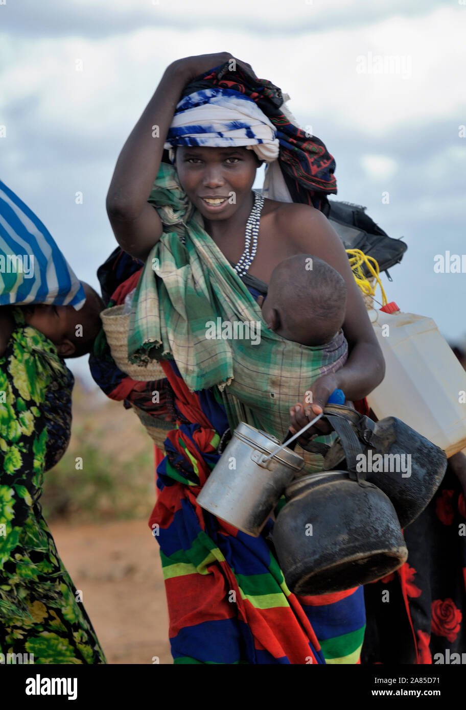 A newly arrived refugee mother carries her family's belongings through the Dadaab camp in northeastern Kenya. Stock Photo