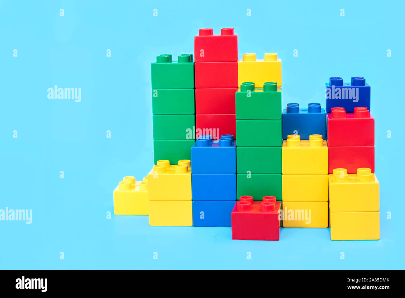 Bar graphs plastic building blocks toy bricks on blue background. Stock Photo