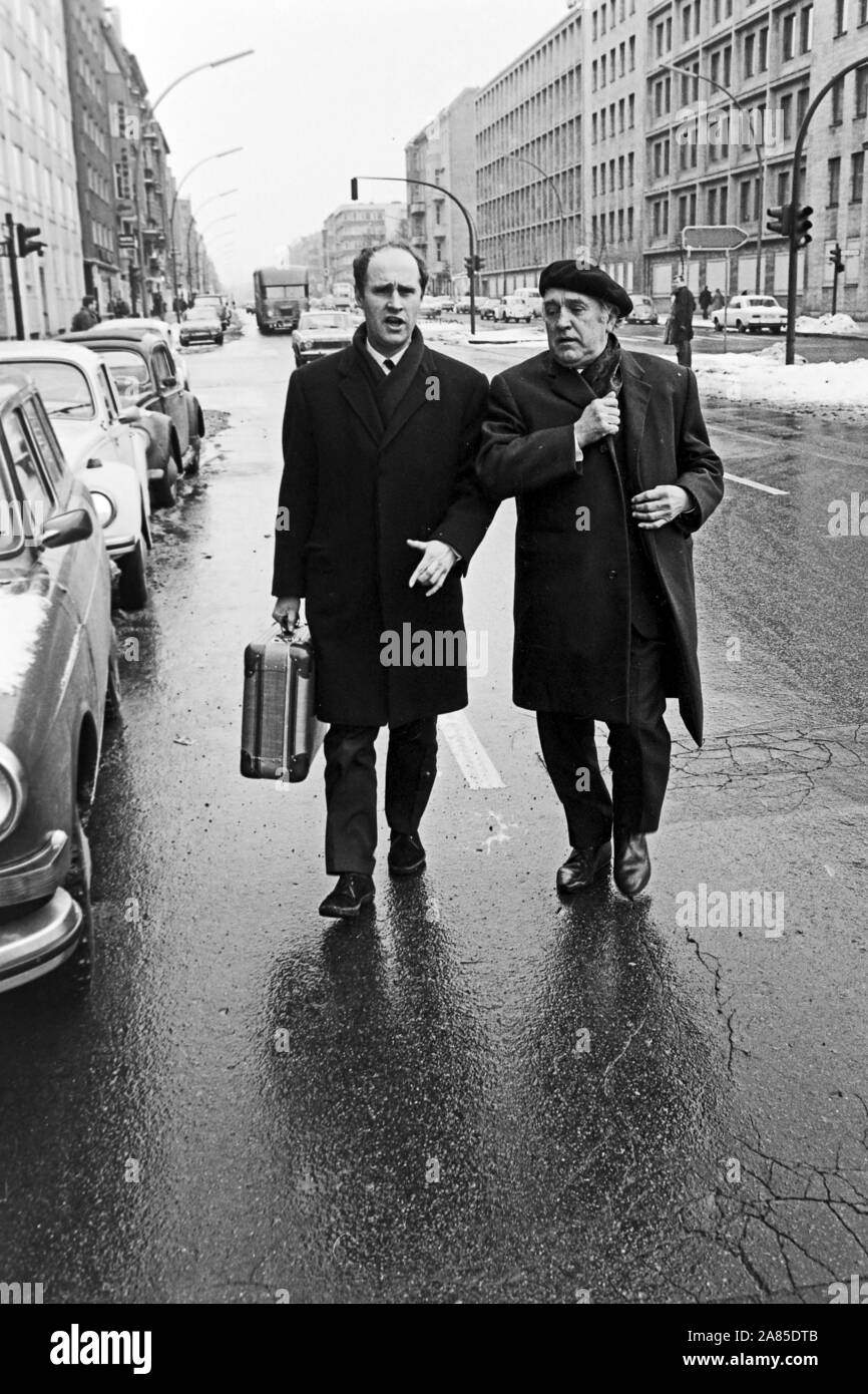 Zwei Männer gehen über eine regennasse winterliche Straße in Berlin, Deutschland 1970. Two men walking in a rainy winterly street in Berlin, Germany 1970. Stock Photo