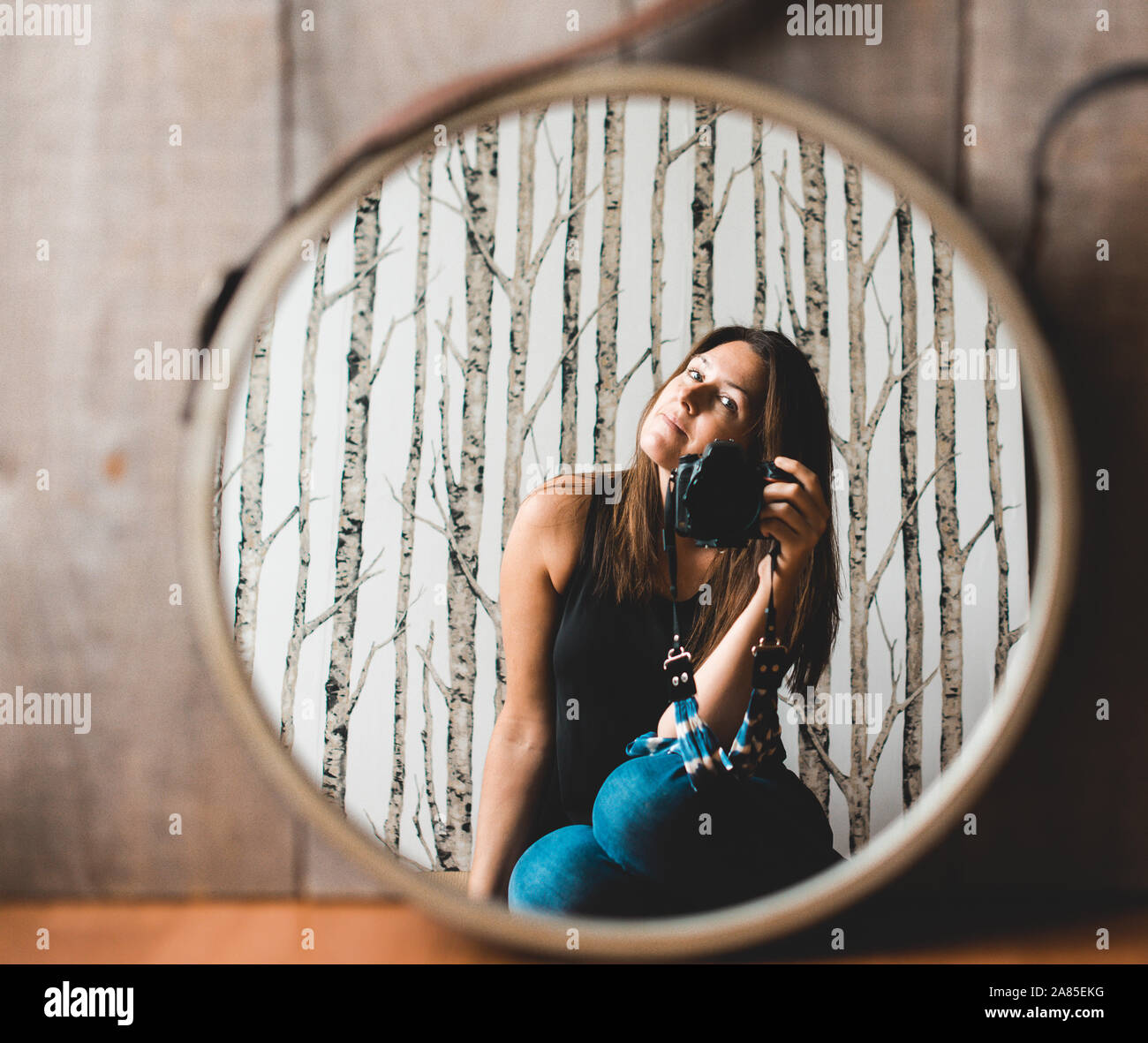 Woman holding camera taking photo of her reflection in the mirror. Stock Photo