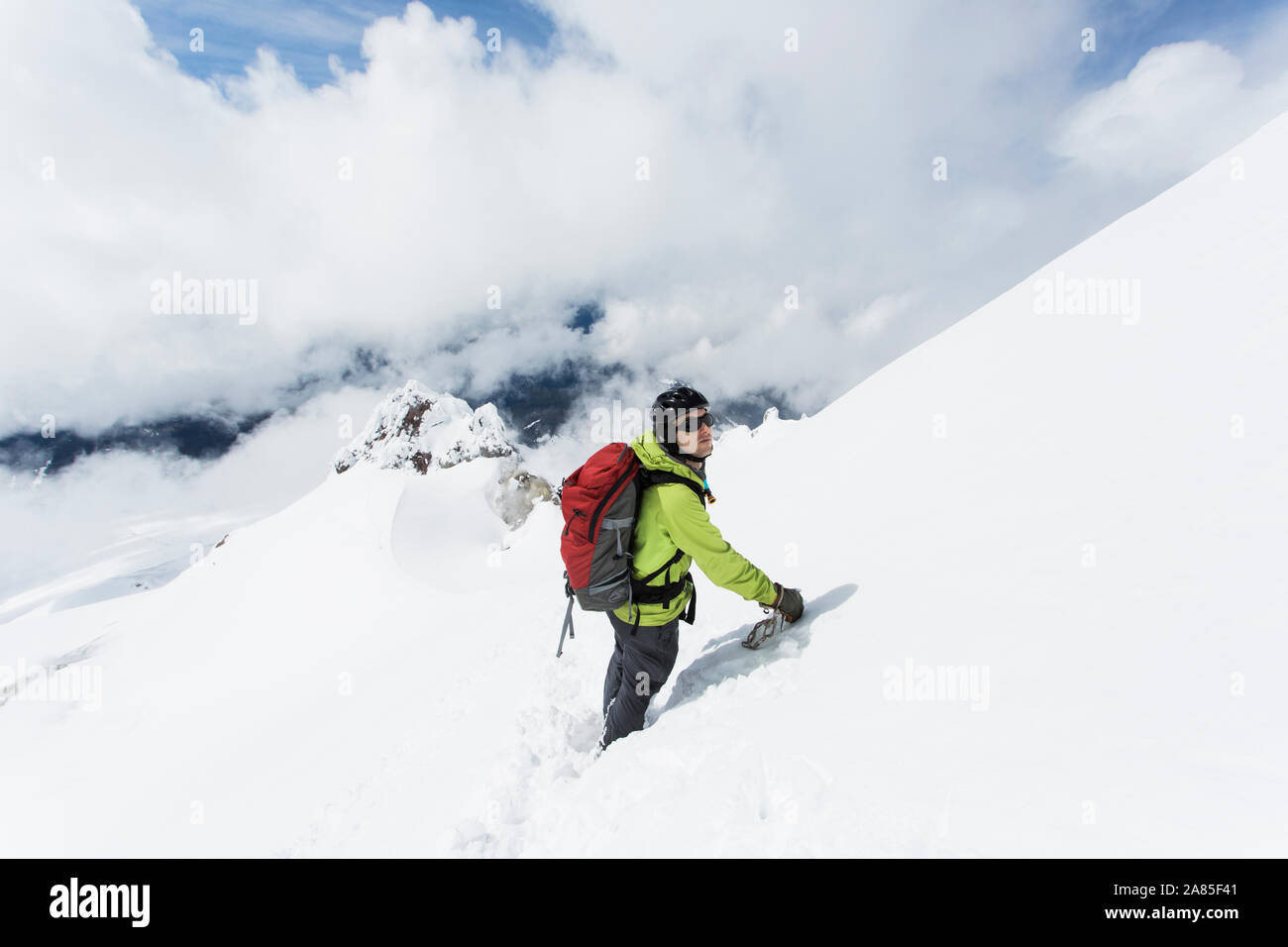A young man descends from the summit of Mt. Hood on a cloudy day. Stock Photo