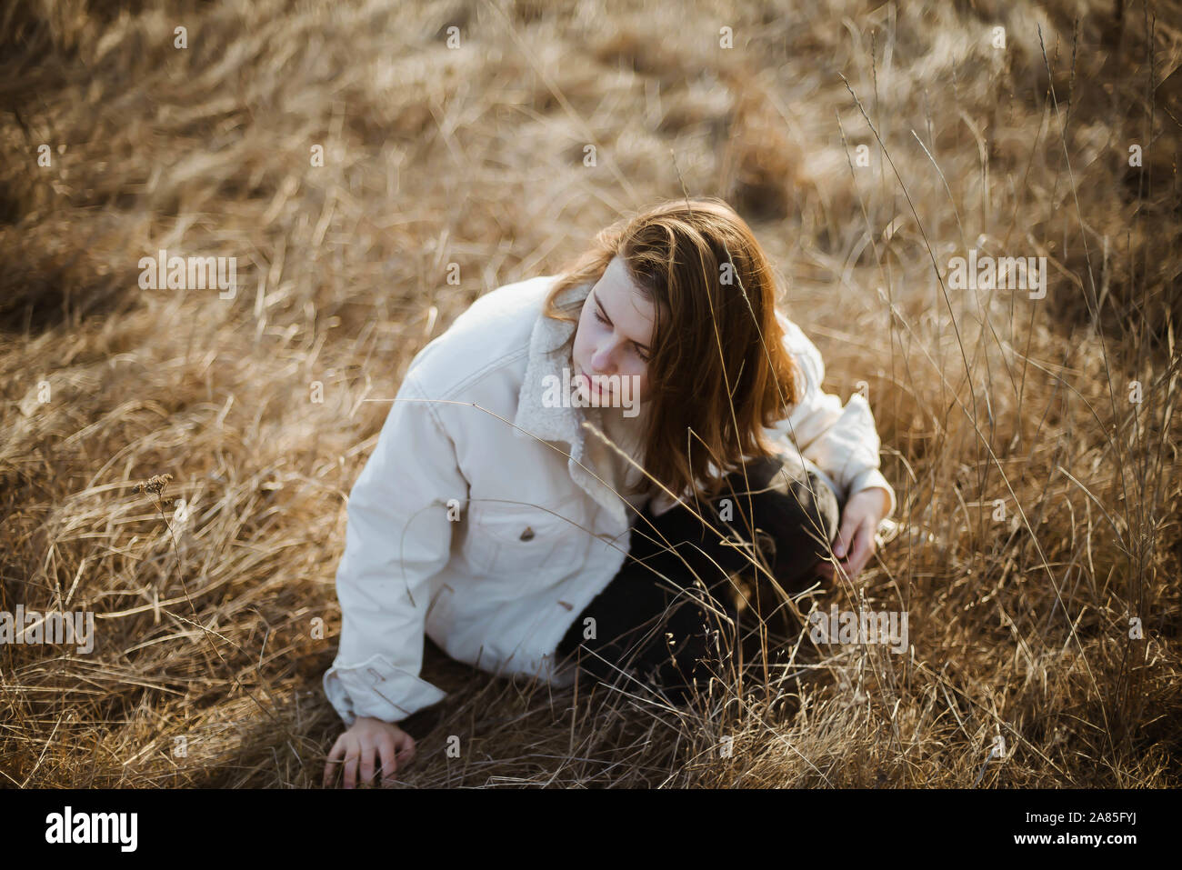 View from above on  woman  sitting  on soft dry grass Stock Photo
