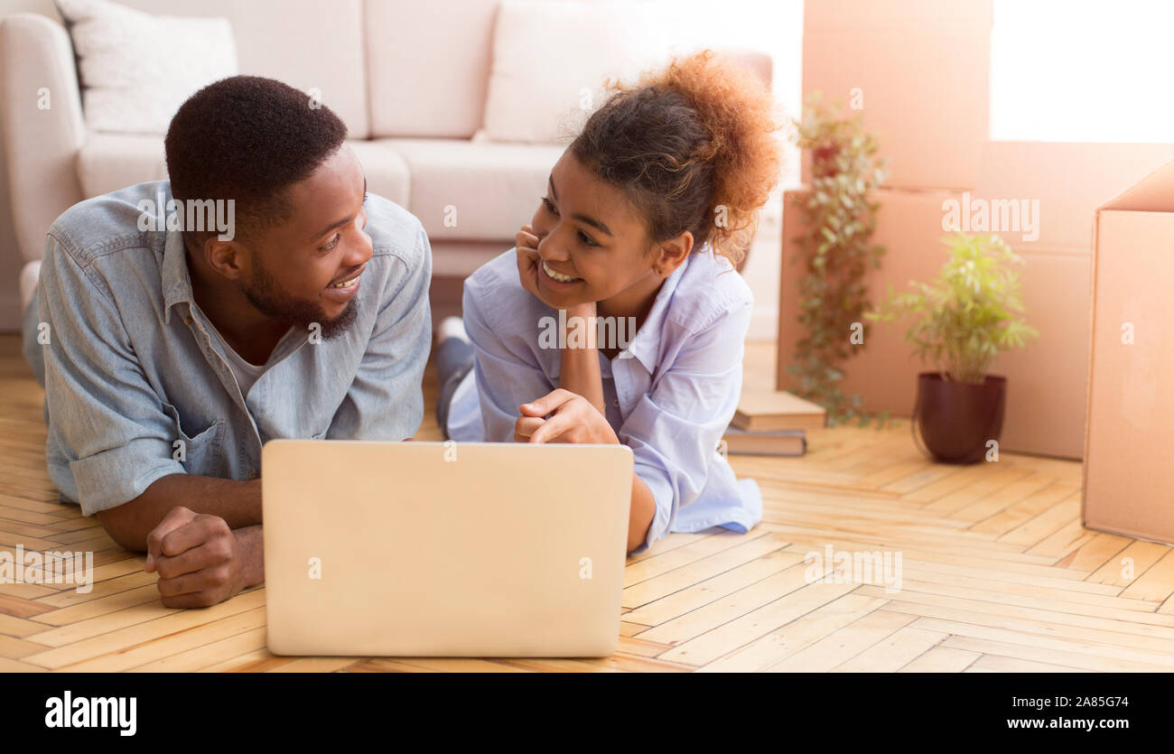 Afro Couple Using Laptop Lying On Floor In New House Stock Photo - Alamy
