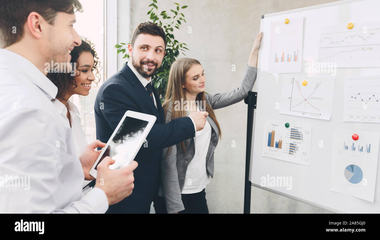 Young business colleagues discussing over charts on board Stock Photo