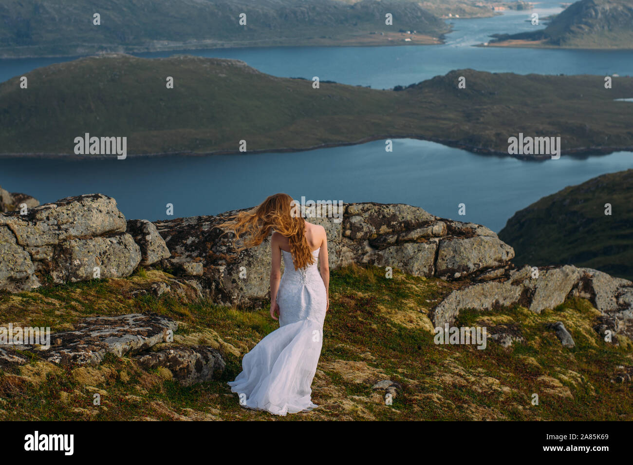 Back Of Girl In Wedding Dress In Mountains Looking To Fjord