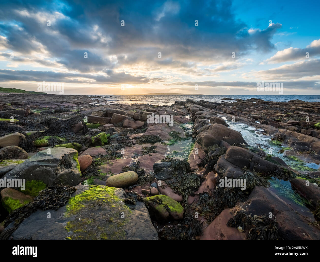 The rugged coastline from John O'Groats in the north of Scotland on a dusky sunset evening with the island of Stroma visible in the distance. Stock Photo