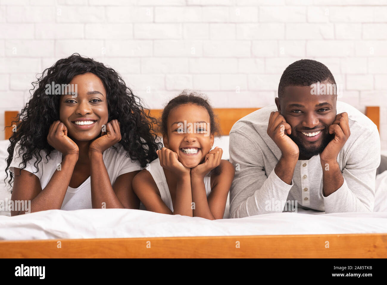 Portrait of happy black family lying on bed together Stock Photo - Alamy