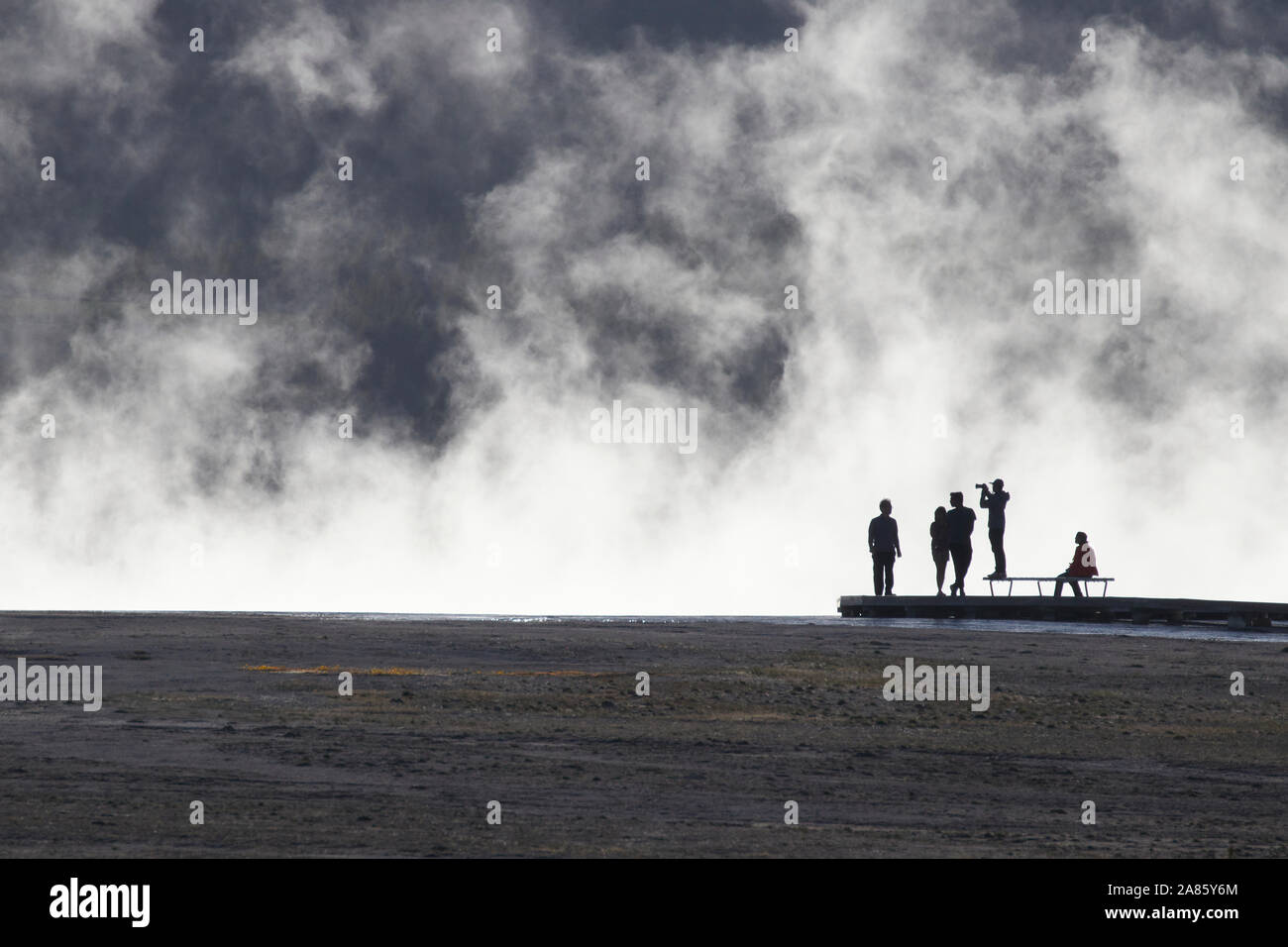 Visitors are silhouetted against plumes of steam at Grand Prismatic Hot Springs in Yellowstone National Park, Wyoming, USA Stock Photo