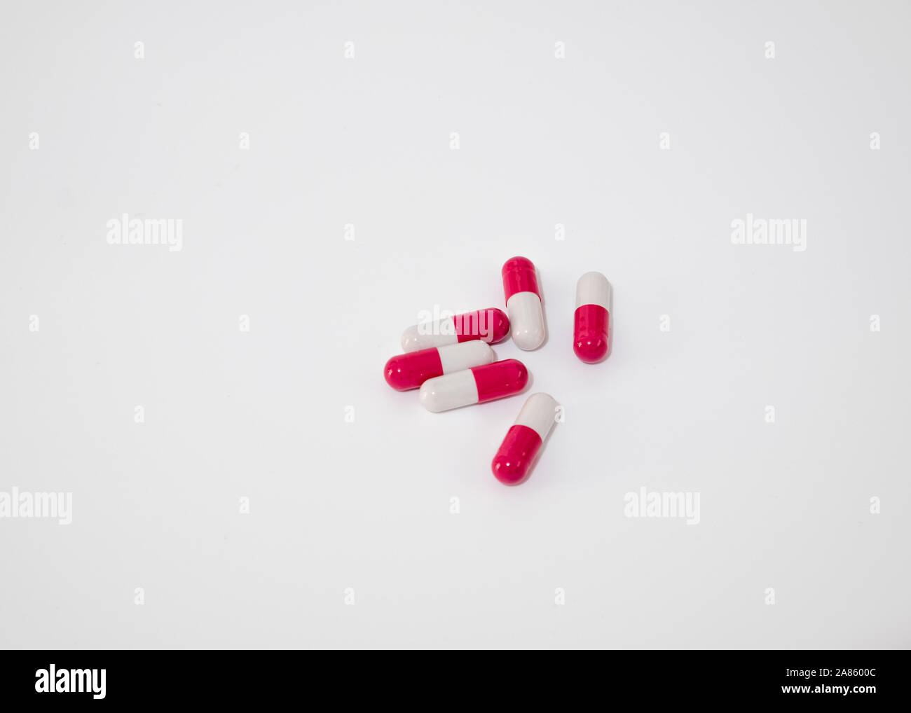 Many white and red piled capsules photographed against a white background. Stock Photo