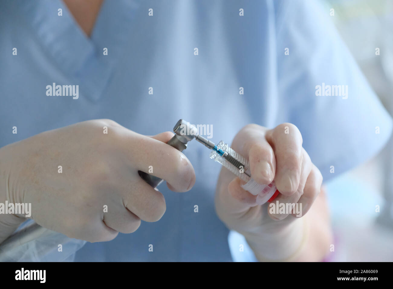 Hands of a dental surgeon in protective gloves with a tool for treating