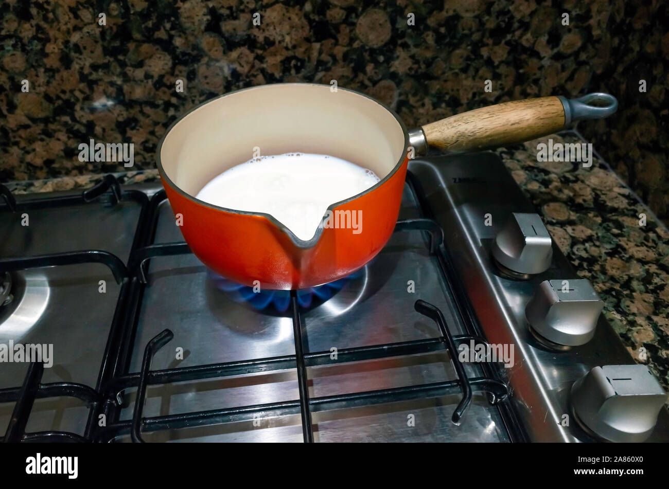 Milk in a saucepan on a gas stove burner Stock Photo - Alamy