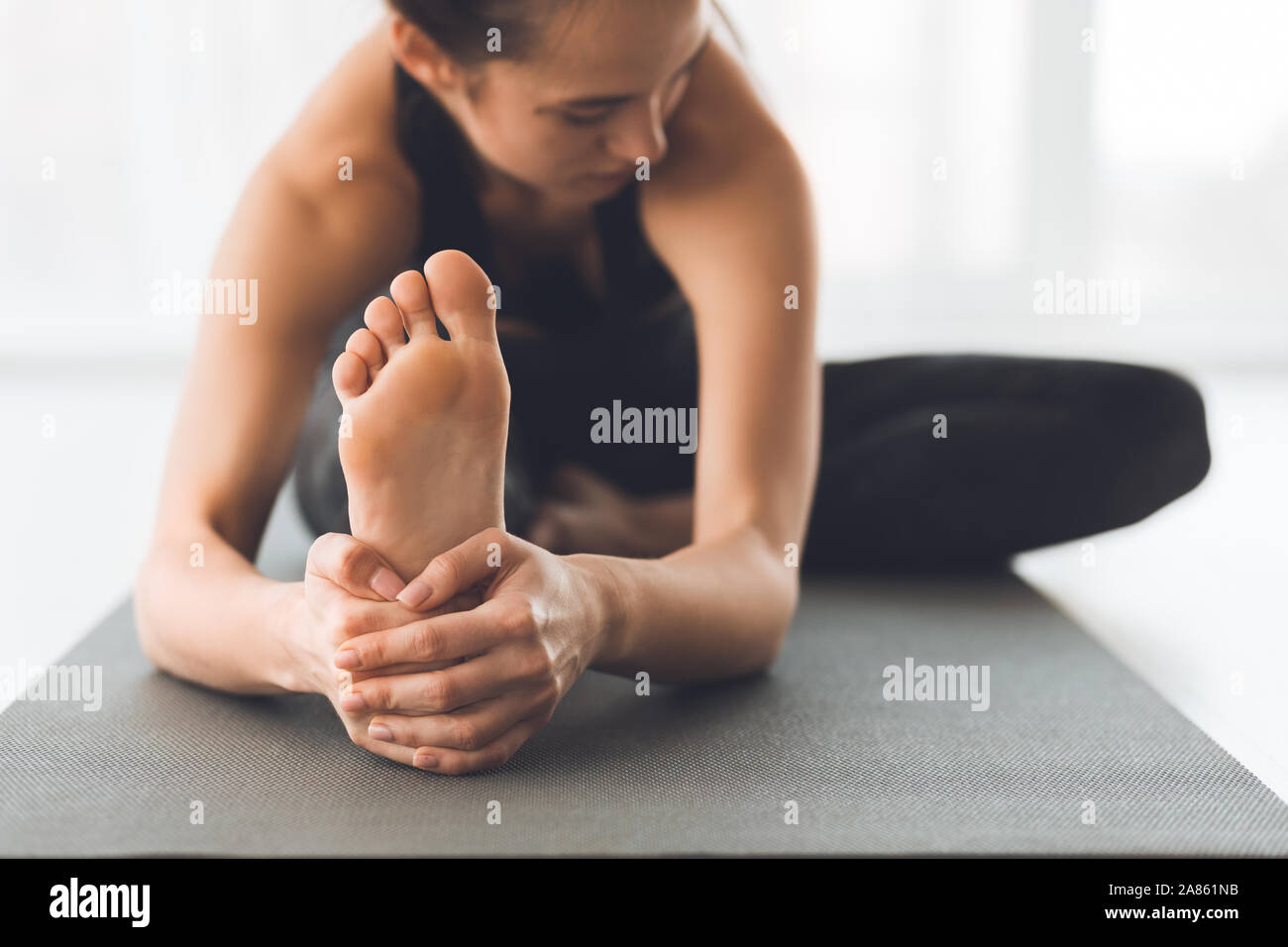 Fit woman warmup stretching, training indoors, focus on foot Stock Photo