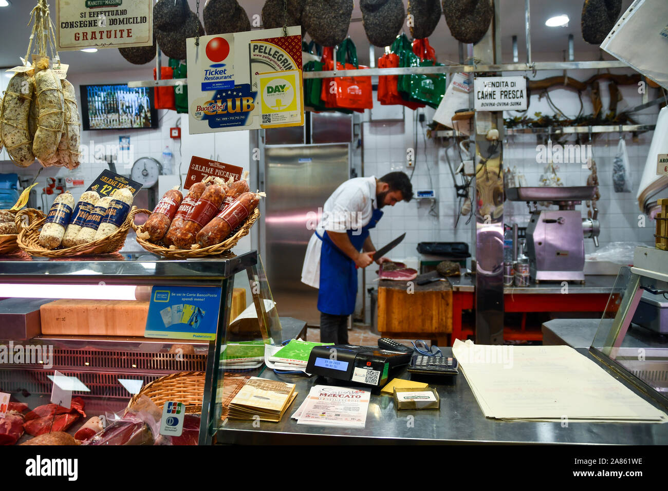 Counter of a butcher shop inside the Central Market of San Lorenzo with a butcher cutting a ham in the background, Florence, Tuscany, Italy Stock Photo