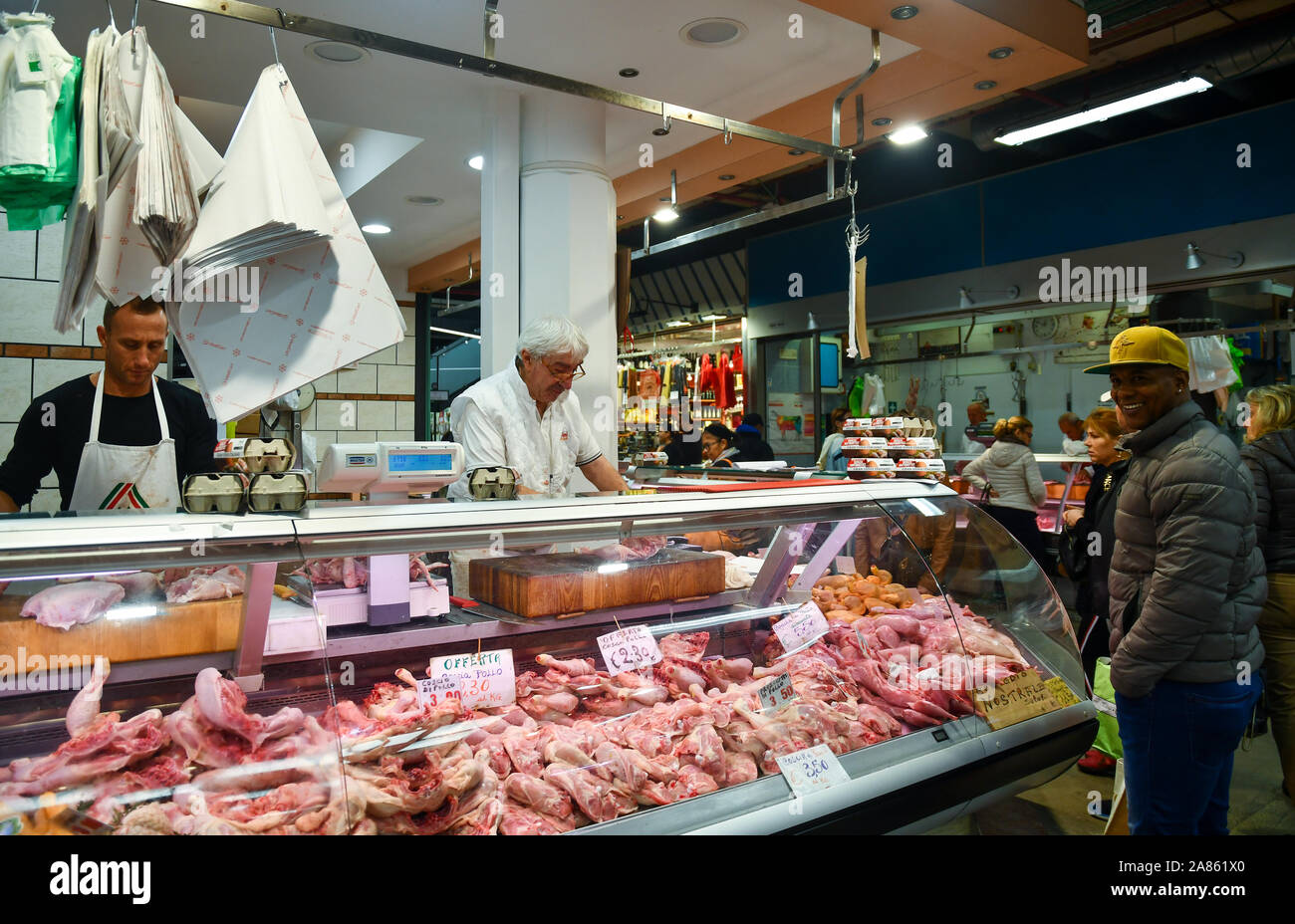 A butcher shop inside the Central Market of San Lorenzo in the city center of Florence with butchers and customers, Tuscany, Italy Stock Photo