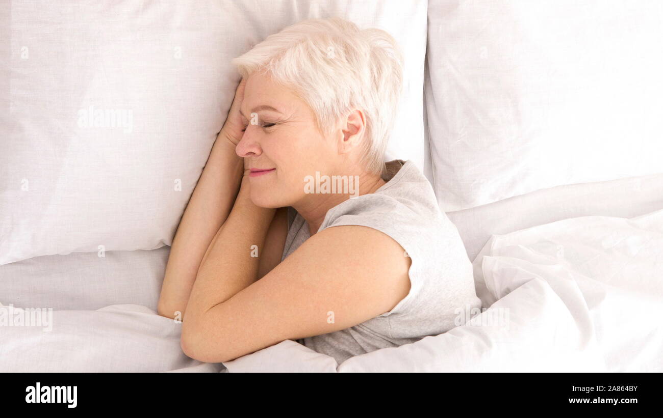 Healthy senior woman napping in bed, top view Stock Photo