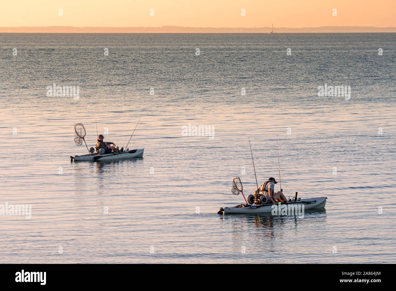Two sea anglers fishing from pedal drive kayaks / pedal driven kayak at sunset Stock Photo