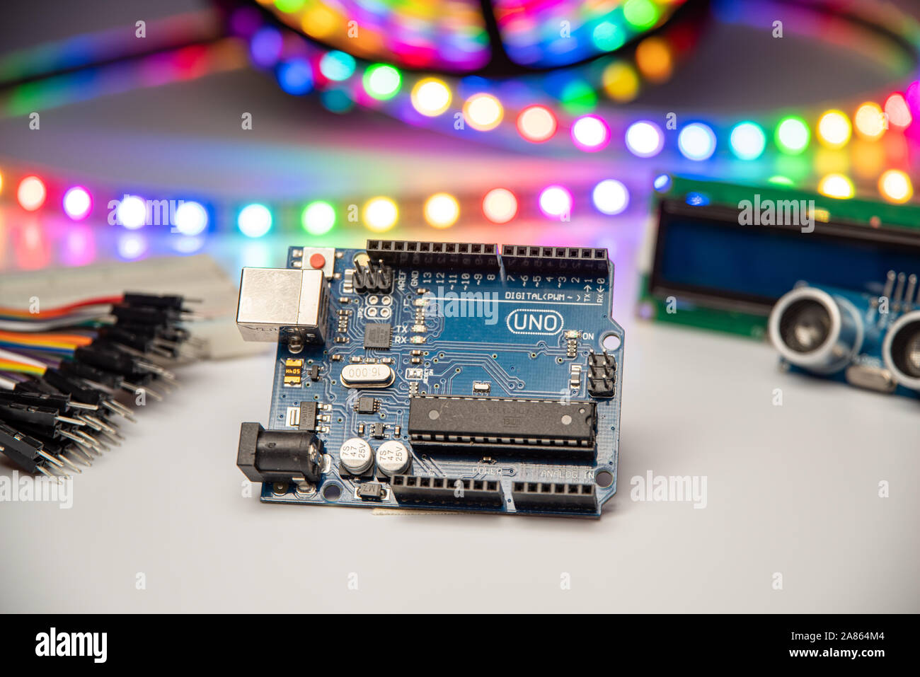 Arduino Uno displayed with LED strip, jumper wires, breadboard, LCD display, and ultrasonic sensor. Stock Photo