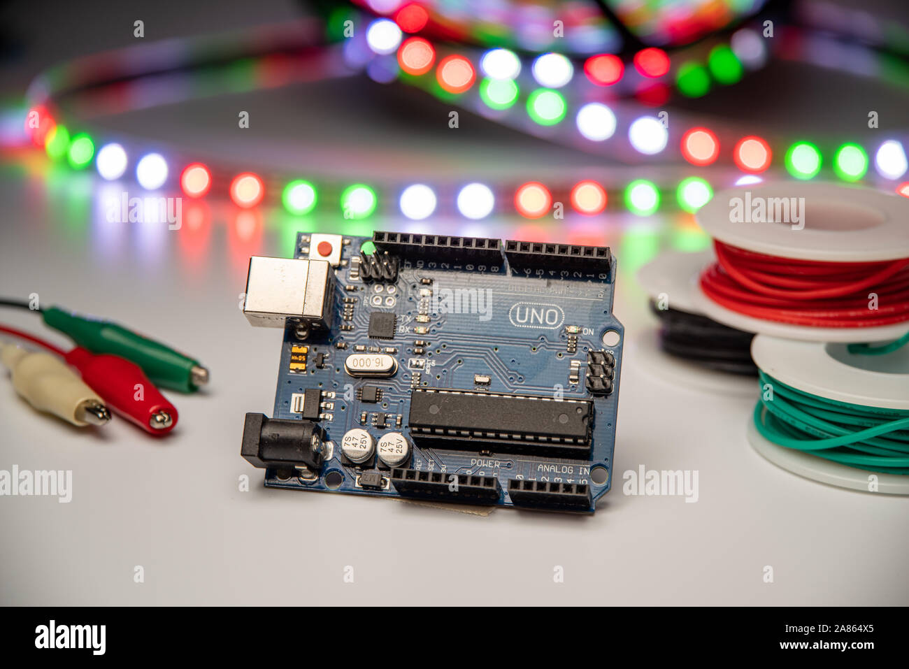 Arduino Uno displayed with LED strip, alligator clip leads, and hookup wire. Stock Photo