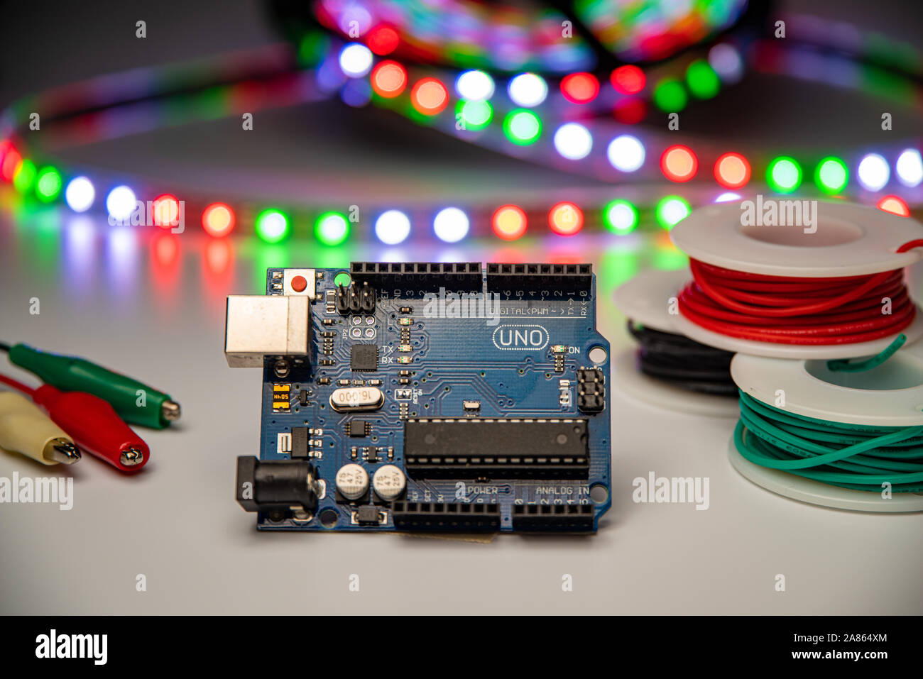 Arduino Uno displayed with LED strip, alligator clip leads, and hookup wire. Stock Photo