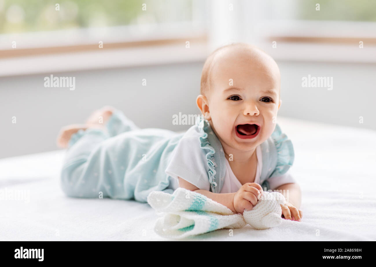 crying baby girl lying on white blanket Stock Photo Alamy