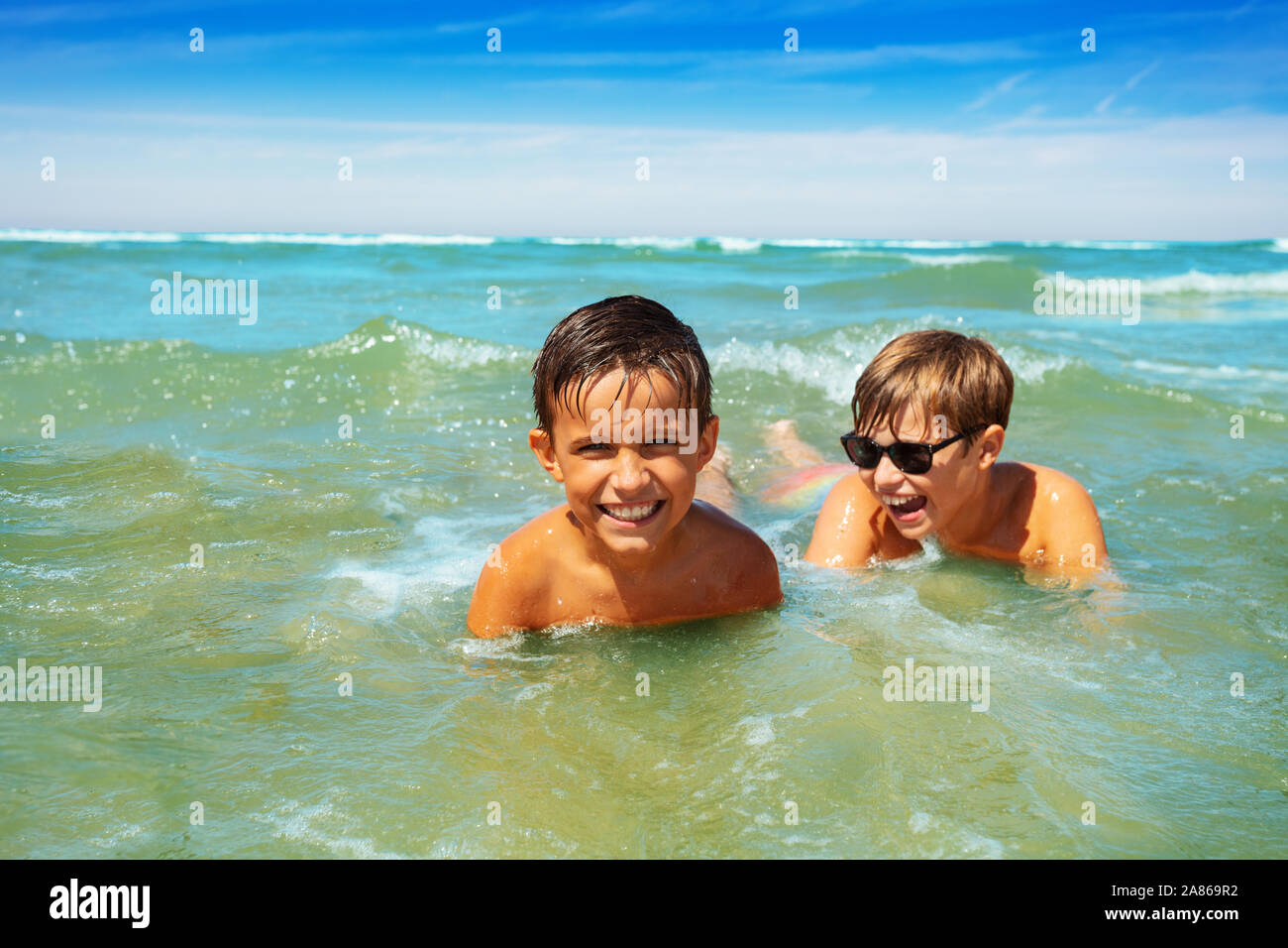 Two boys play in shallow water sea waves on beach Stock Photo - Alamy