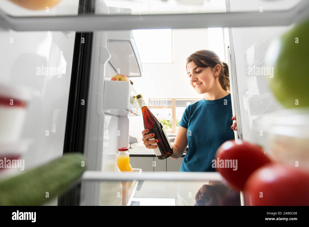 happy woman taking wine bottle from fridge at home Stock Photo Alamy