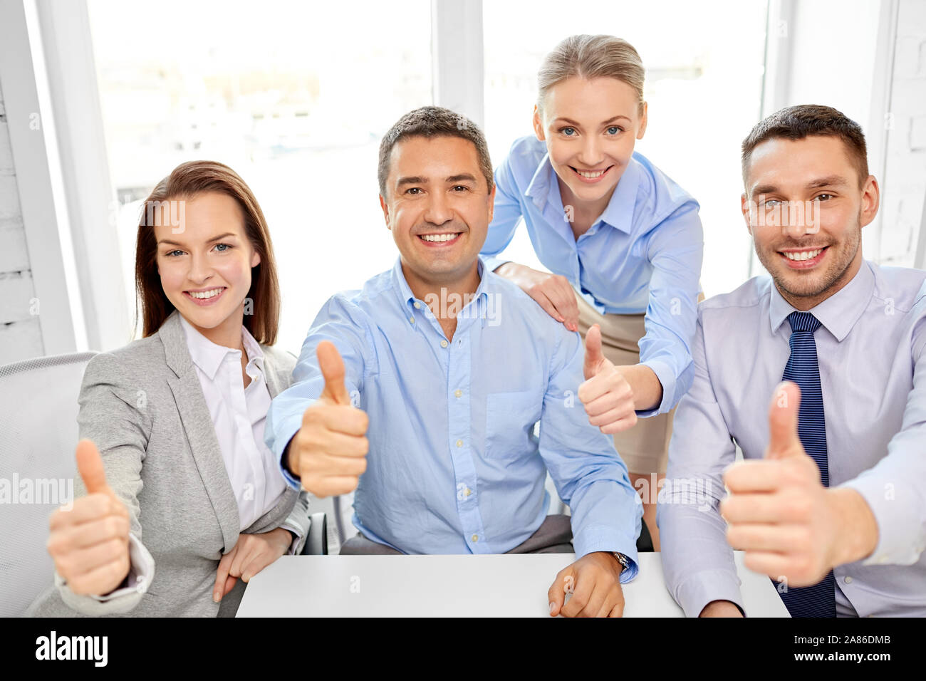 happy business team showing thumbs up at office Stock Photo - Alamy