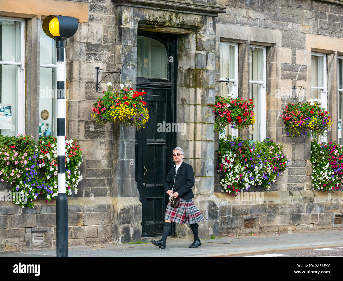 Scottish man wearing kilt walking in street by a Belisha beacon, Tay Street, Perth City, Scotland, UK Stock Photo
