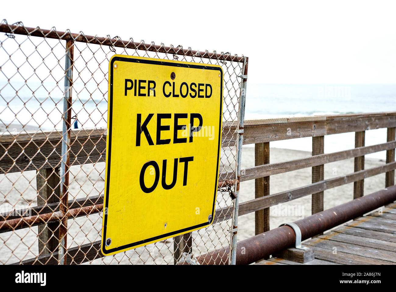 Bright yellow sign at a beach pier that reads Pier Closed Keep Out Stock Photo