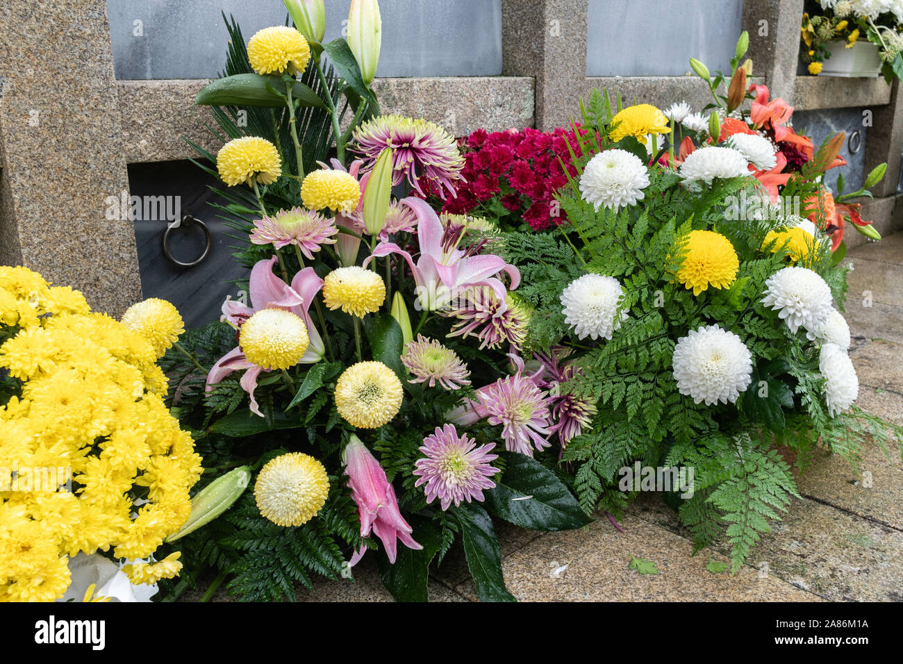 Bouquet of colorful flowers during christian All Saints Day event lying in the tomb in the cemetery. Death concept Stock Photo