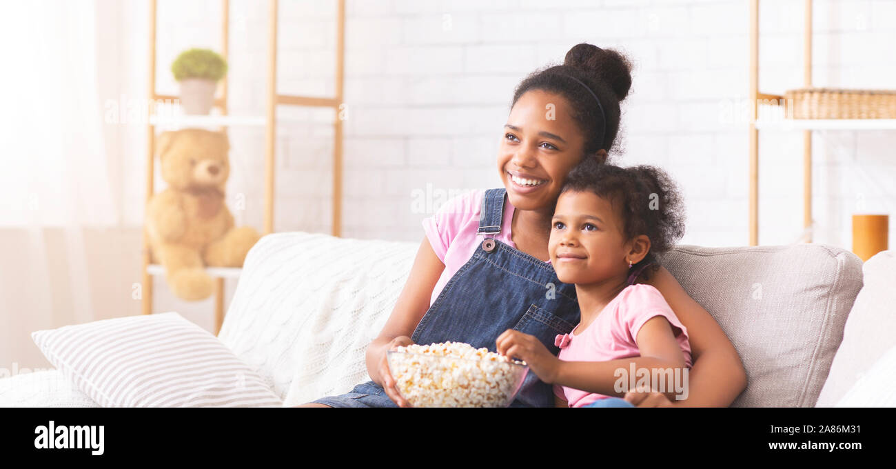 African american sisters enjoying cartoon with popcorn at home Stock Photo