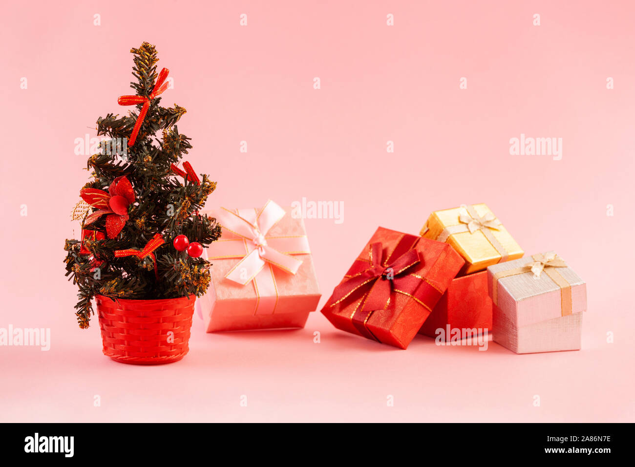 Christmas concept. Decorated christmas tree with four gift boxes on a pink background. Stock Photo