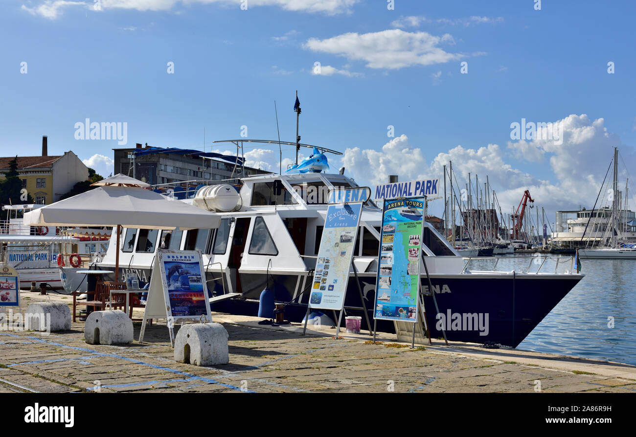 Sightseeing boat along with advertising hoardings for trips to see national park or dolphin watching in Pula, Croatia Stock Photo