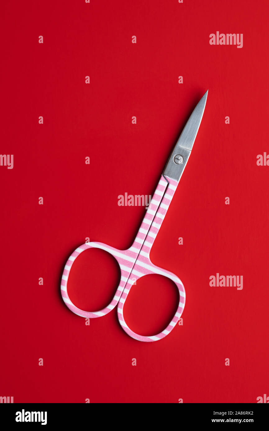 Pink manicure scissors on red background. Top view. Stock Photo