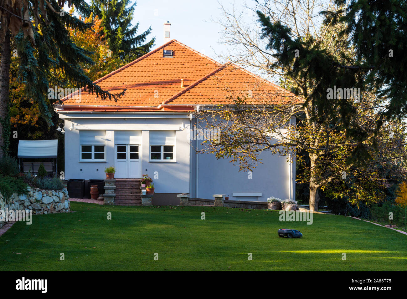 Robot robotic lawn mower mowing grass in garden of house, Sopron, Hungary Stock Photo