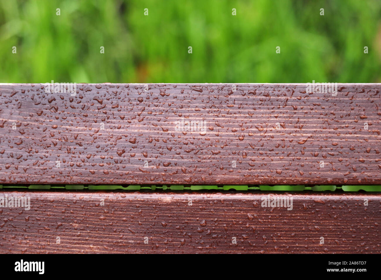 Wood planks covered by water drops on green grass background, rainy