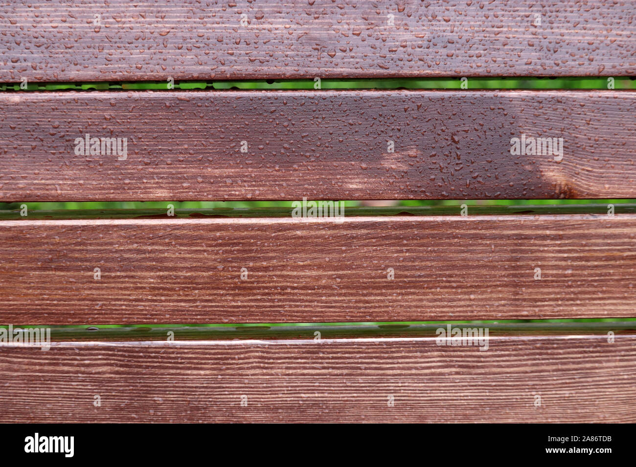 Wood planks covered by water drops on green grass background, rainy