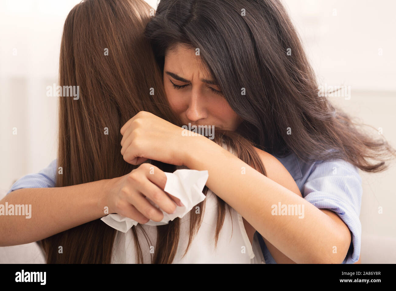 Woman Embracing Depressed Friend Sitting On Sofa Indoor, Selective Focus Stock Photo