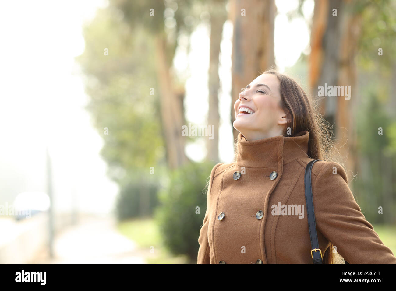 Happy woman breathing deeply fresh air standing in a foggy park in ...
