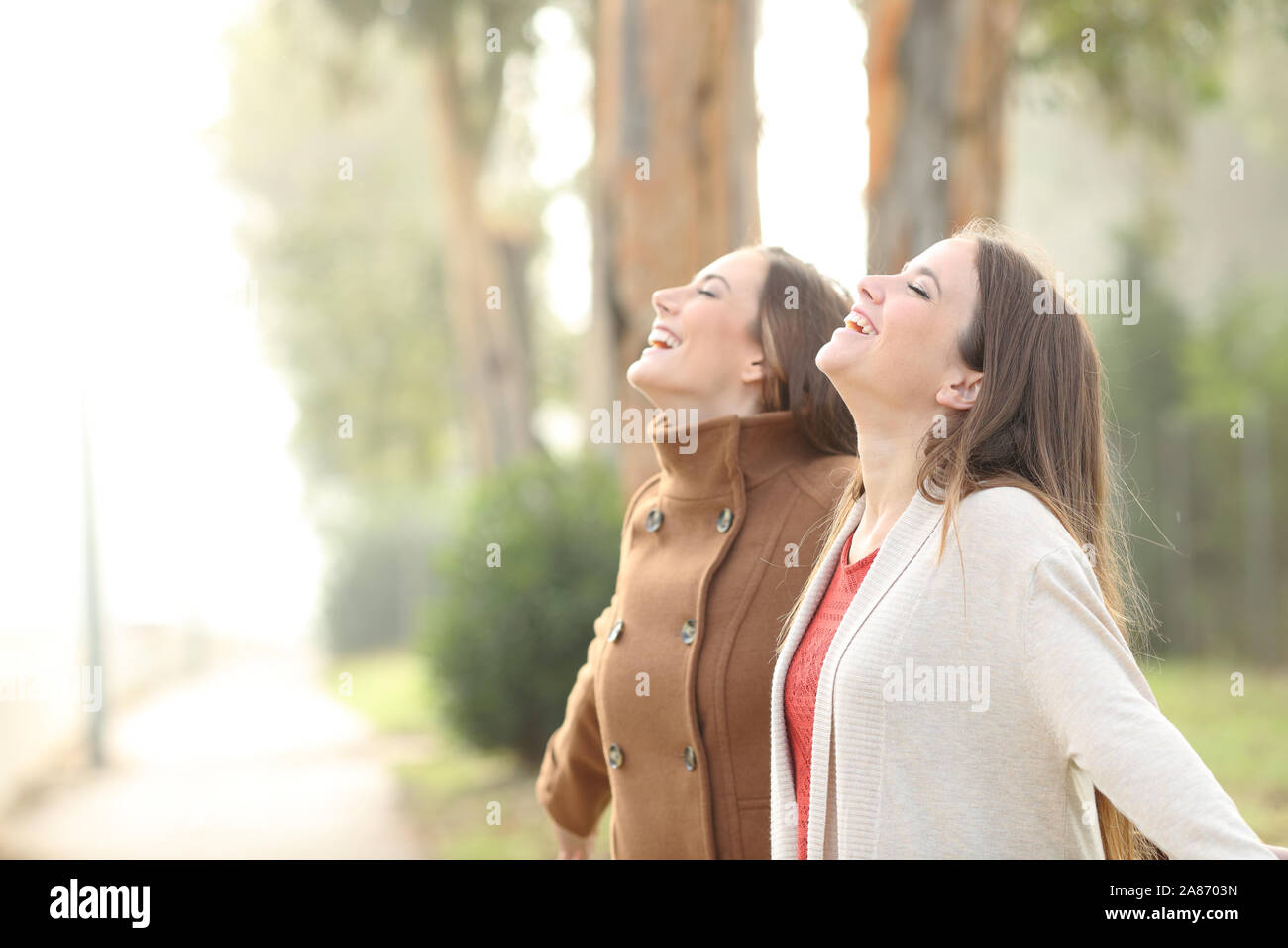 Two happy women breathing deeply fresh air standing in a park Stock ...