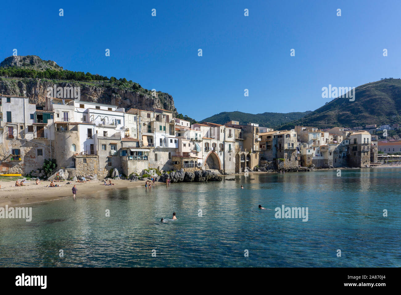 The Old Town of Cefalú, Sicily, Italy, viewed from the pier area with the rocky crag known as La Rocca looming over the town. Stock Photo