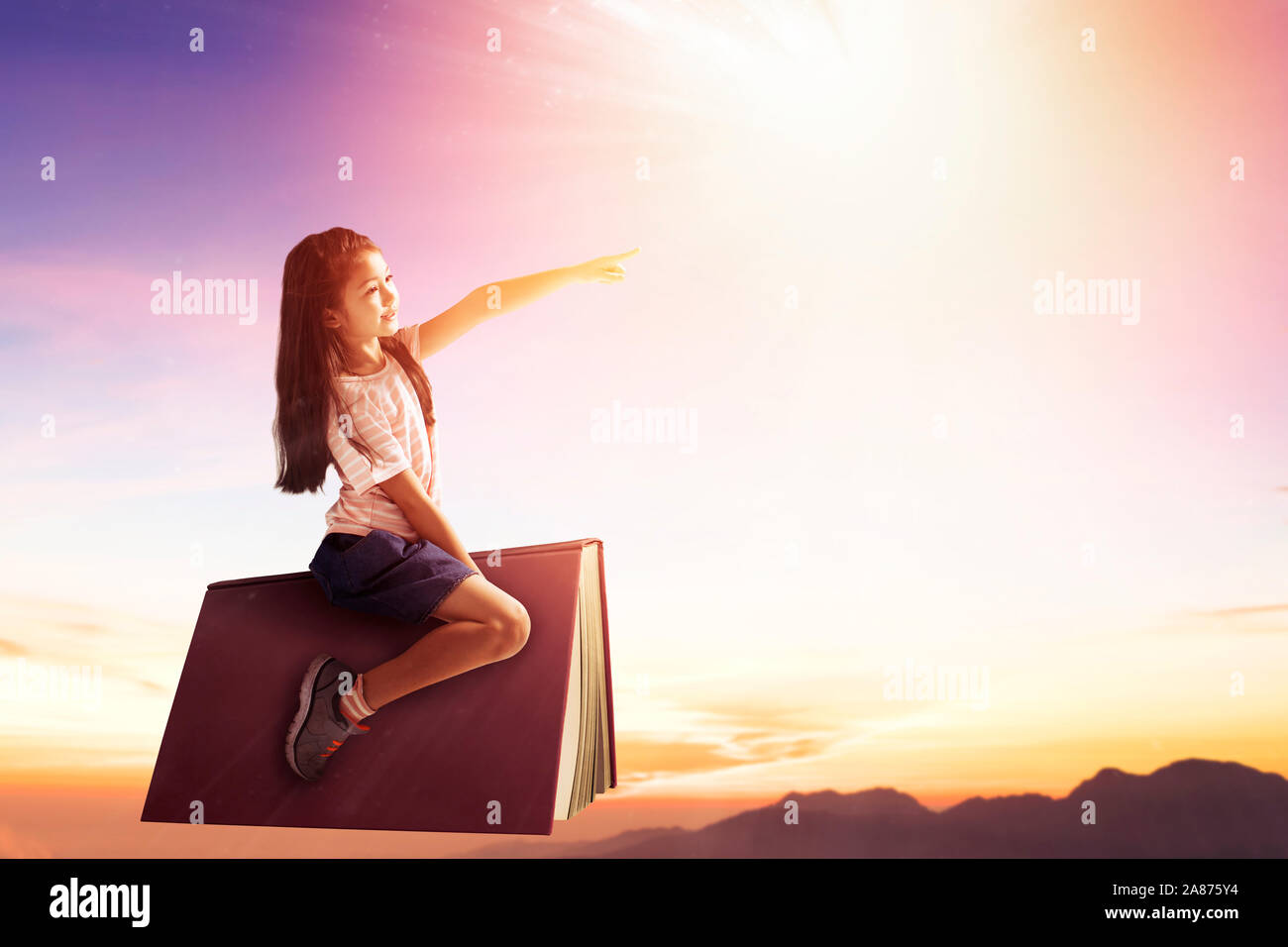 happy little girl on book and flying in the sky Stock Photo - Alamy