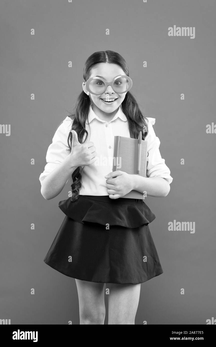 success concept. happy school girl in uniform and party glasses. small child with notebook. literature lesson education. writing in workbook. children literature. get information from book. Stock Photo