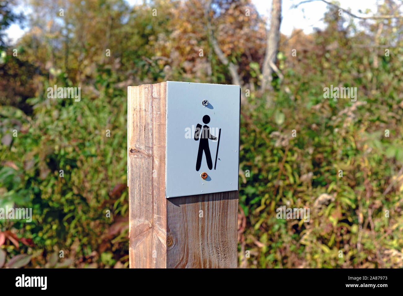 Wooden post with hiker caricature indicating the existnece of a hiking path in the outdoors in Northeast Ohio. Stock Photo