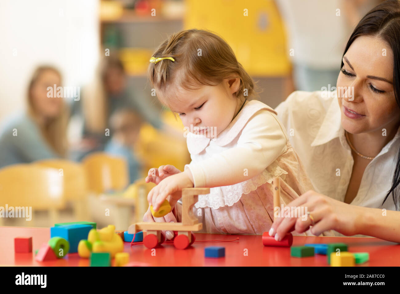 Child building blocks with a teacher in the nursery Stock Photo
